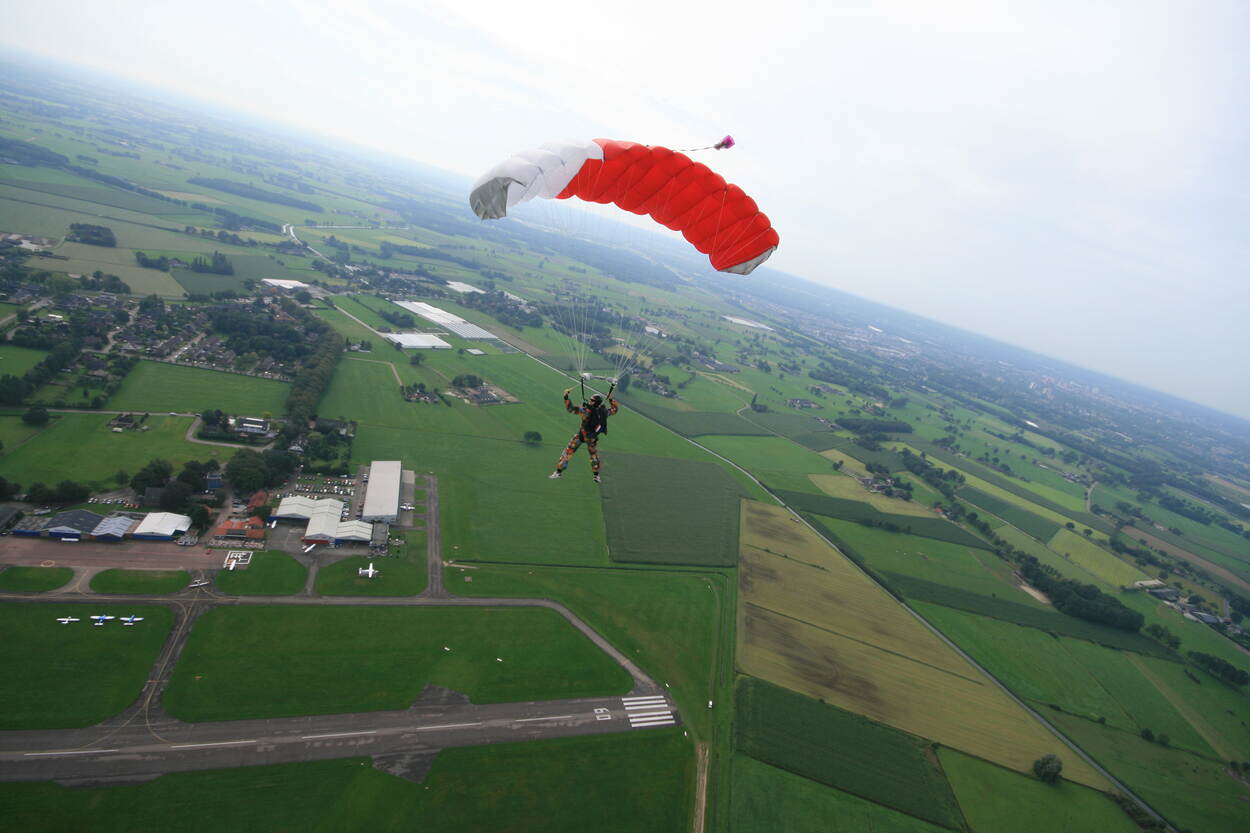 Parachutist in de lucht met een rechthoekige parachute.